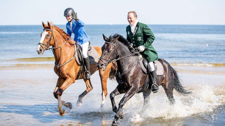 Zwei Reiter/innen, im Hintergrund Meer.