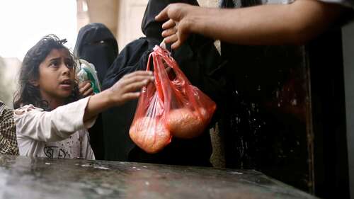 Ein Mädchen bekommt eine Tüte mit Reis.