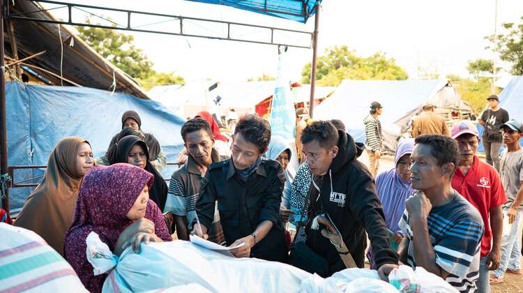 Männer und Frauen stehen beisammen und schauen auf eine Liste.