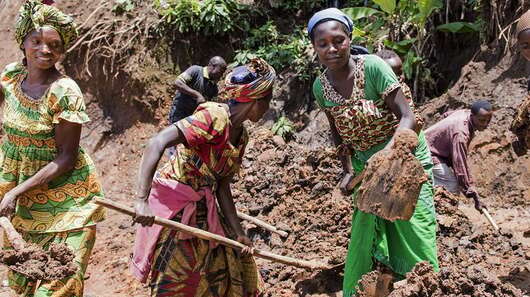 Frauen mit Schaufeln in der Hand.