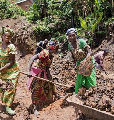 Frauen mit Schaufeln in der Hand.