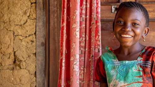 Portraitfoto von lächelndem Mädchen vor einer Tür