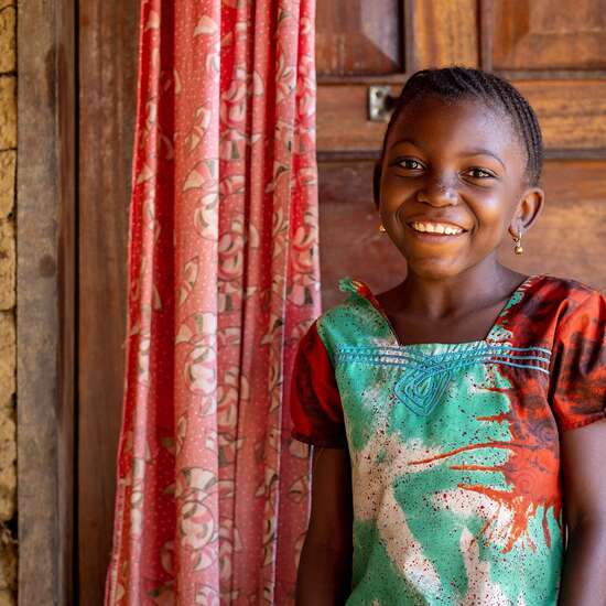 Portraitfoto von lächelndem Mädchen vor einer Tür