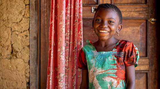 Portraitfoto von lächelndem Mädchen vor einer Tür