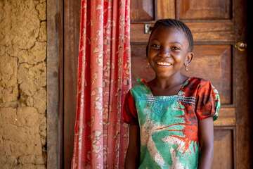 Portraitfoto von lächelndem Mädchen vor einer Tür