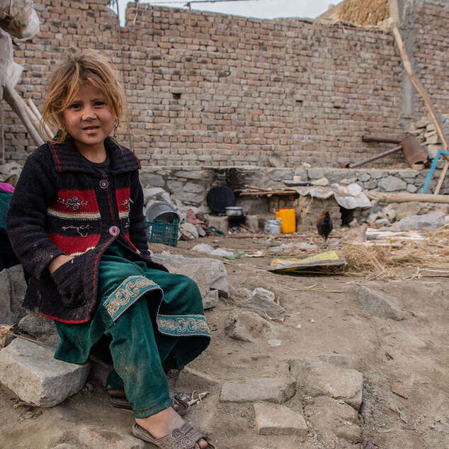 Mädchen sitzt vor Trümmern in Afghanistan