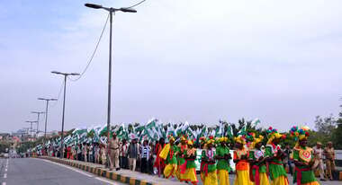 Indigene Demonstranten stehen in tarditionseller Kleidung und mit wehenden Fahnen am Straßrand.