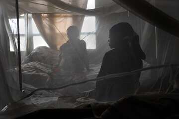 Zwei Frauen sitzen auf einem Bett, davor ein Netz