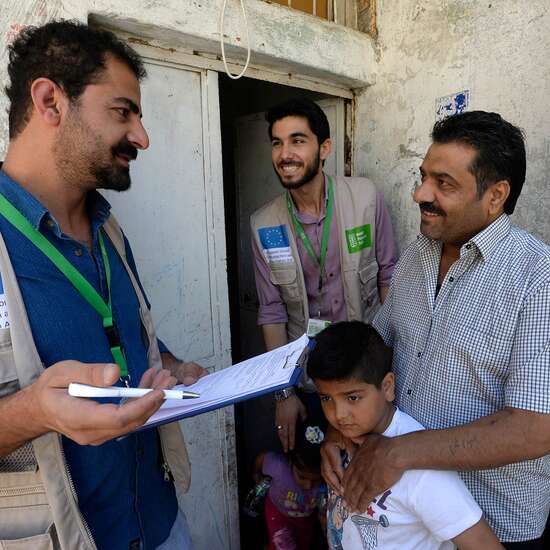 Zwei Welthungerhilfe-Männer reden mit einem Mann und einem kleinen Kind.