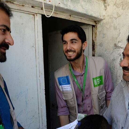 Zwei Welthungerhilfe-Männer reden mit einem Mann und einem kleinen Kind.