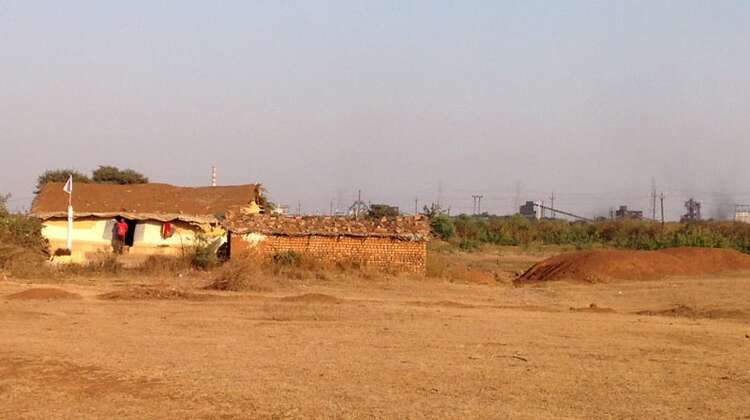 Das Haus einer Adivasi-Familien ist von Industire umgeben. 