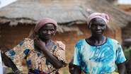 Zwei Kleinbäuerinnen in traditioneller Kleidung stehen vor einer Hütte in Burkina Faso