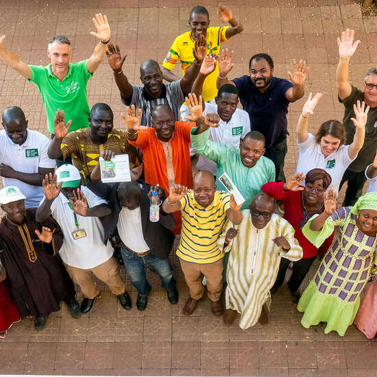 Eine Gruppe von Mitarbeiter*innen schaut Richtung Kamera und winkt