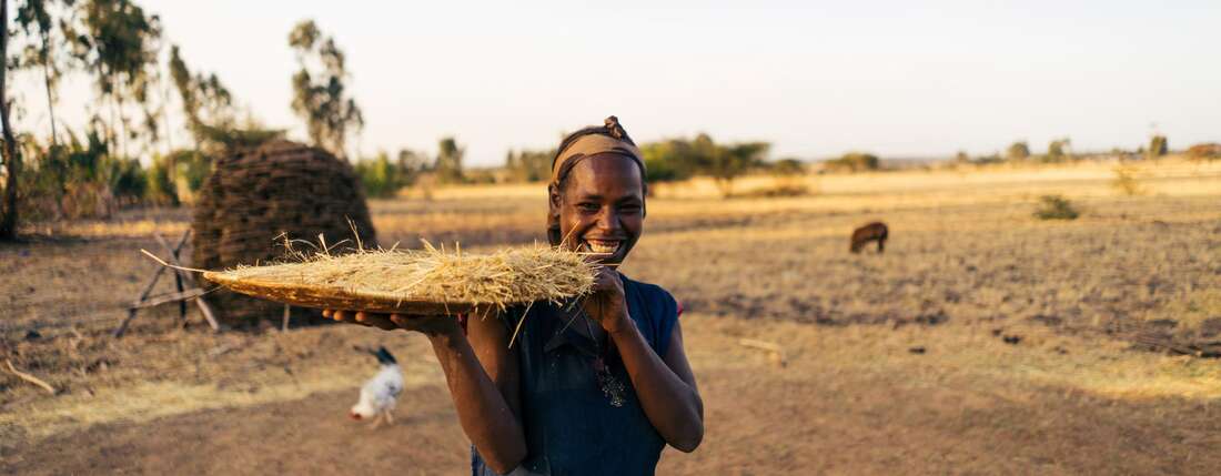 Eine Frau hält ein eine große Platte mit geerntetem Getreide in der Hand