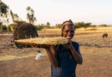 Eine Frau hält ein eine große Platte mit geerntetem Getreide in der Hand