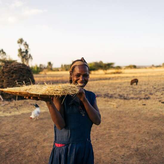 Eine Frau hält ein eine große Platte mit geerntetem Getreide in der Hand