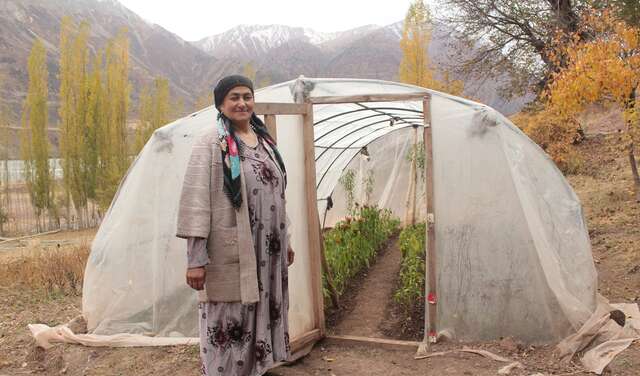 Eine Frau steht vor einem Gewächshaus in Tadschikistan, 2021.