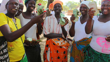 Fünf Frauen halten Geld in die Kamera, das sie als Kredit für ihre Unternehmensgründung erhalten haben.
