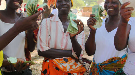 Fünf Frauen halten Geld in die Kamera, das sie als Kredit für ihre Unternehmensgründung erhalten haben.