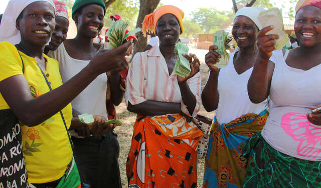 Fünf Frauen halten Geld in die Kamera, das sie als Kredit für ihre Unternehmensgründung erhalten haben.