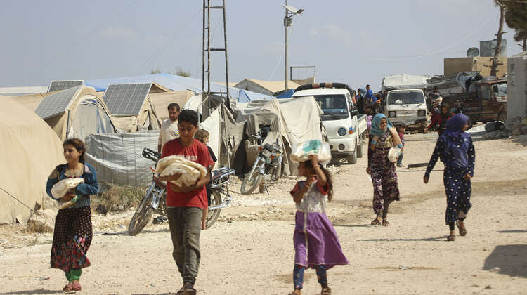 2019-brotverteilung-fluechtlingscamp-idlib-syrien_C_HIHFAD-16-9.jpg Geflüchtete tragen Tüten mit Fladenbrot von einer Verteilung.