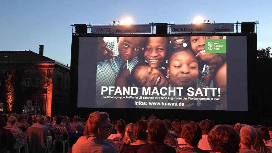 Publikum und Leinwand mit Werbung zu der Aktion "Pfand macht satt" 