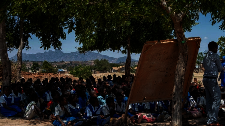 Kinder sitzen auf dem Boden und hören zu.