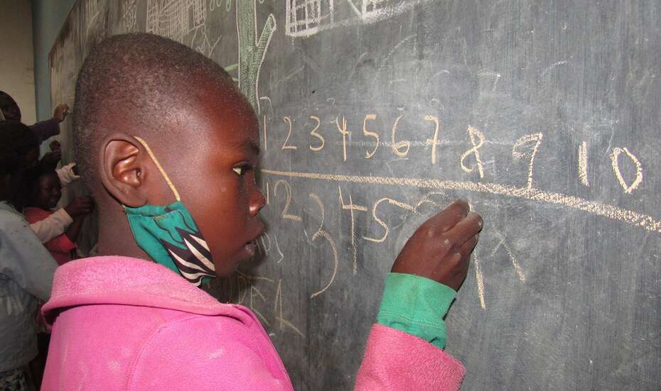 Ein Mädchen steht an der Tafel und rechnet, Malawi 2021. 