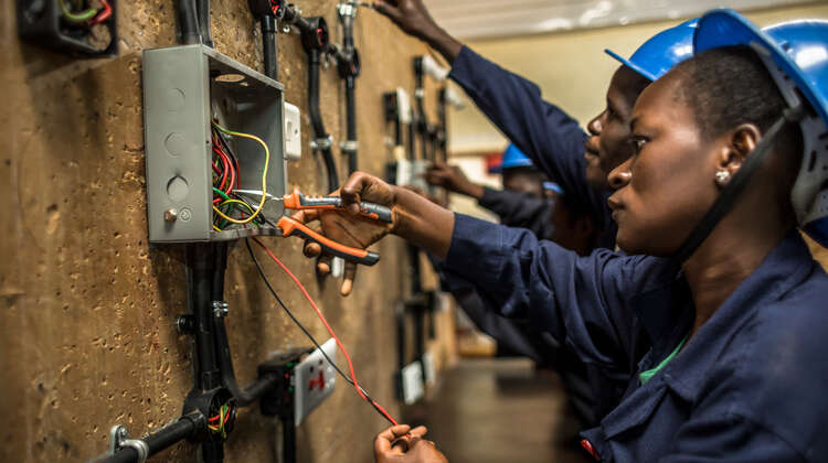 Eine Auszubildende steht an der Wand und arbeitet.