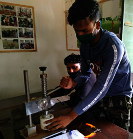 Ein junger Mann repariert eine LED-Glüchbirne, Indien 2021.