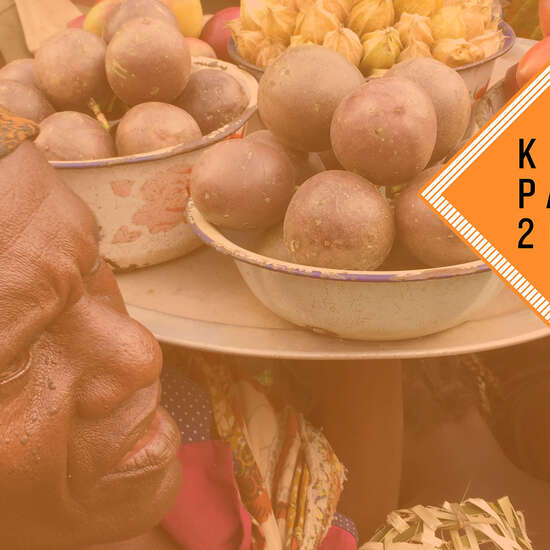 Verkauf auf einem Markt im Kongo: Frauen halten Tabletts mit Obst in die Höhe. Oben rechts ist das "Kompass 2021"-Logo.