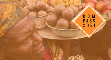 Verkauf auf einem Markt im Kongo: Frauen halten Tabletts mit Obst in die Höhe. Oben rechts ist das "Kompass 2021"-Logo.