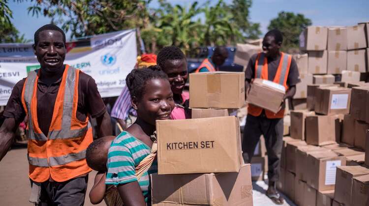 Eine Frau läuft von einer Hilfsgüter-Verteilung weg. In ihren Händen hält sie Kartons.