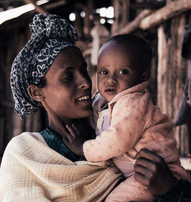 Eine Frau hält ein Baby im Arm und lächelt.