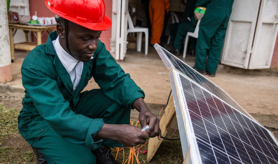 Der Auszubildende Cypriano Kwebiiha installiert eine Solaranlage.