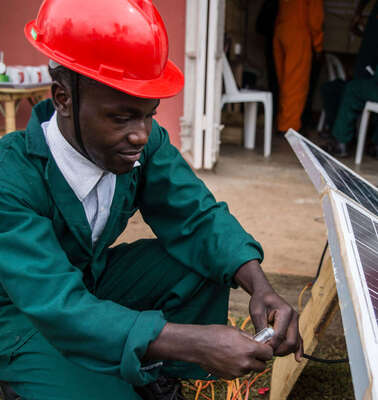 Der Auszubildende Cypriano Kwebiiha installiert eine Solaranlage.