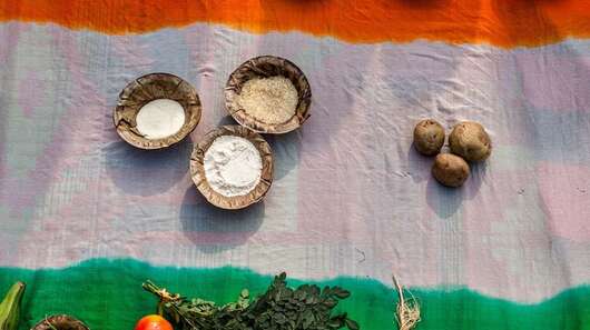 Auf dem Boden liegt eine indische Flagge, darauf stehen verschiedene Lebensmittel.