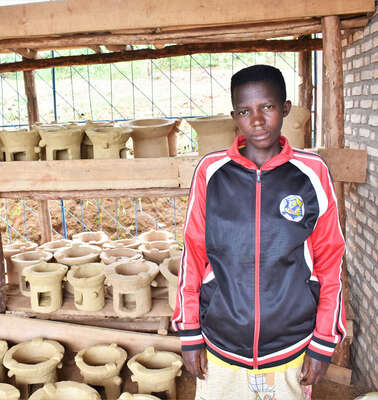 Eine junge Frau zeigt die neuen, effizienten Öfen, die sie baut, Burundi 2021.