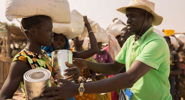 Ein Mitarbeiter der Welthungerhilfe reicht einer Frau im Flüchtlingscamp Bentiu Hilfsgüter