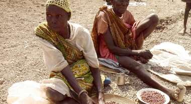 Zwei Frauen sitzen vor Nahrungsmitteln auf dem Boden.