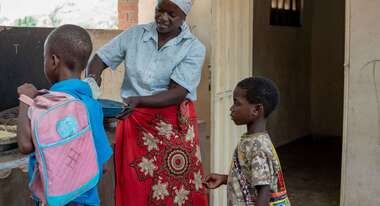 Eine Frau schöpft für Kinder Essen auf ihren Teller