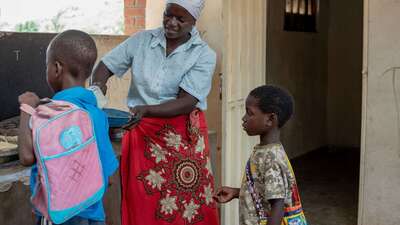 Eine Frau schöpft für Kinder Essen auf ihren Teller