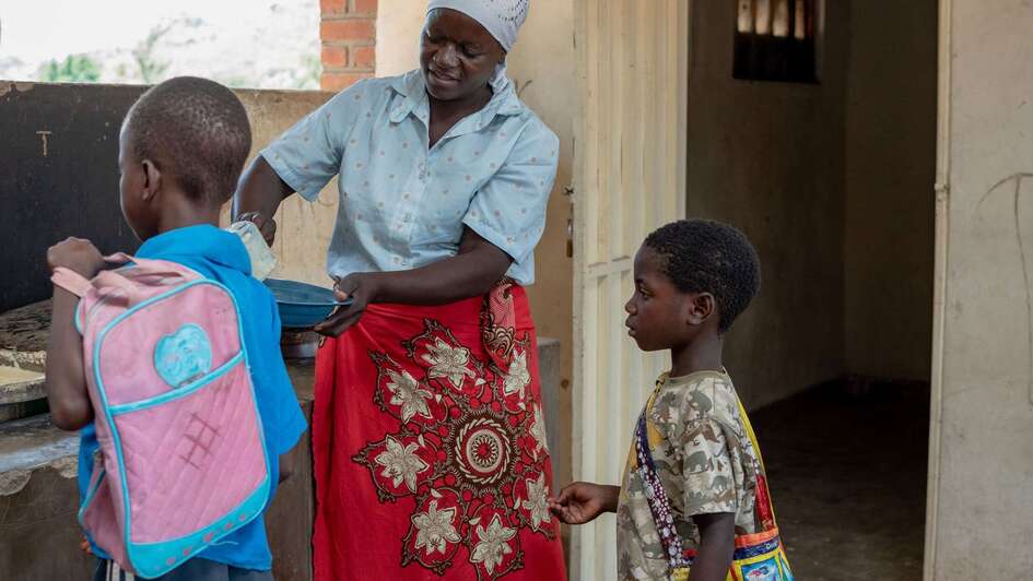 Eine Frau schöpft für Kinder Essen auf ihren Teller
