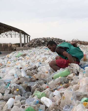 Zwei Personen stehen in einem Meer aus Plastikflaschen.