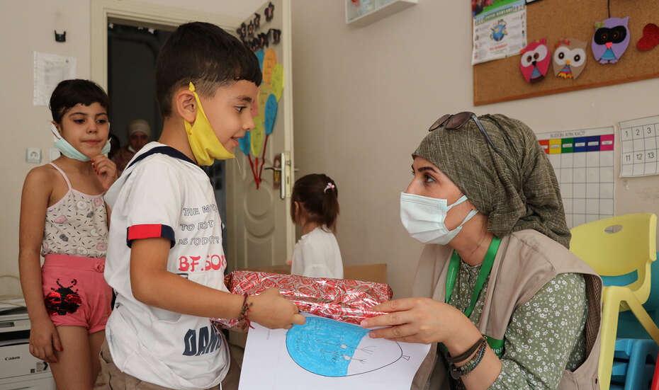 Eine Frau mit Mundschutz und ein Junge mit Mundschutz stehen sich gegenüber.