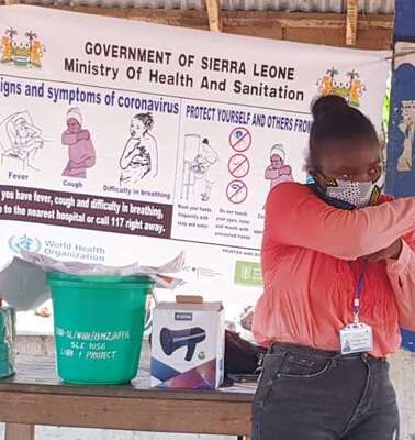 Eine Frau mit Mundschutz demonstriert Schutzmaßnahmen zu Corona.