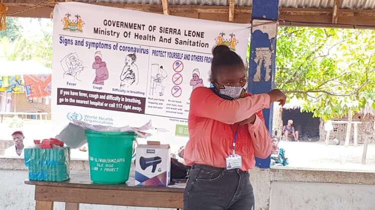 Eine Frau mit Mundschutz demonstriert Schutzmaßnahmen zu Corona.