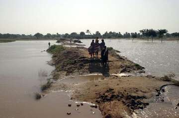 Betroffene gehen über ein letztes Stück Land, welches aus dem Wasser herausragt.
