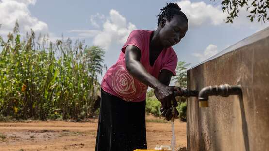 Frau beim Wasserholen an einem Brunnen