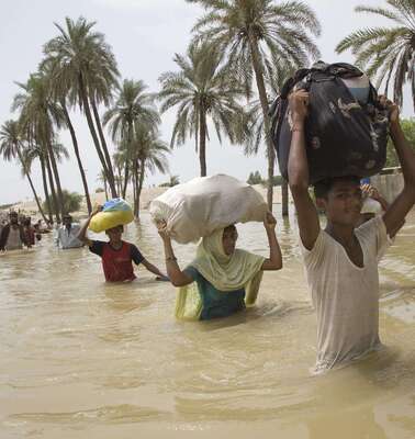 Menschen waten mit Hab und Gut durch Wasser